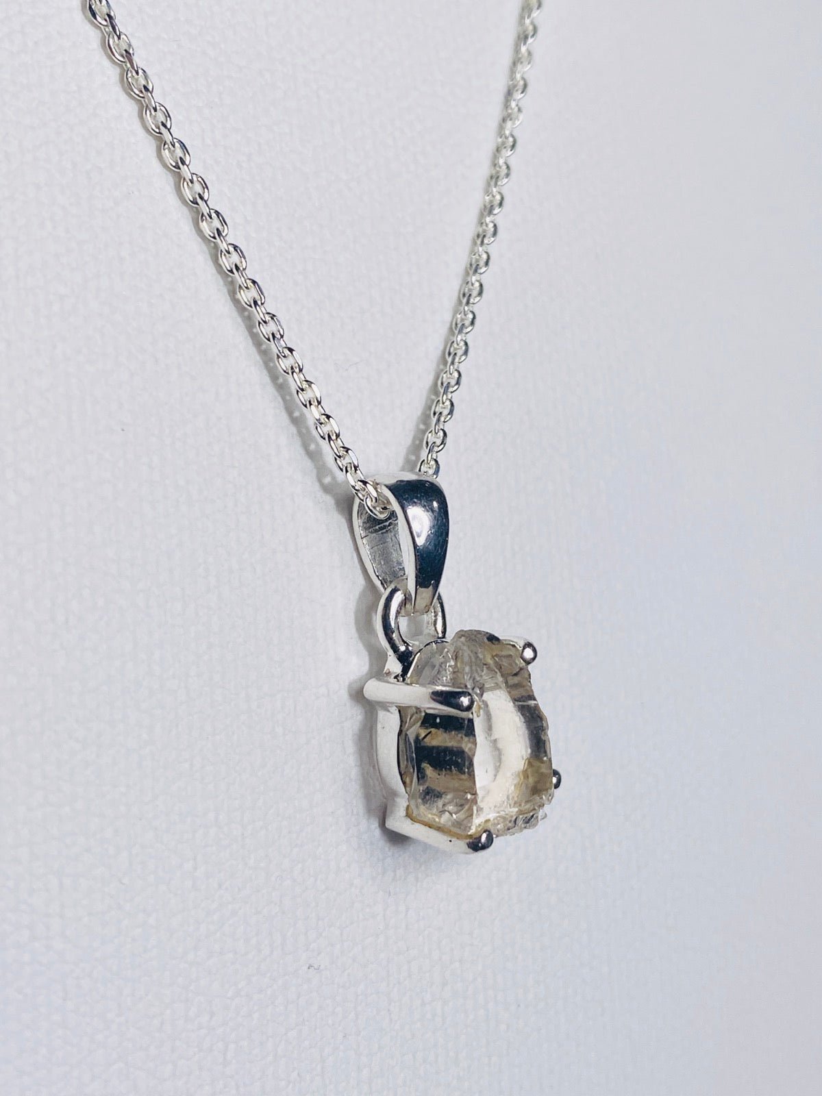 HERKIMER Diamant als Kettenanhänger eingefasst vor weißem Hintergrund an SIlberkette