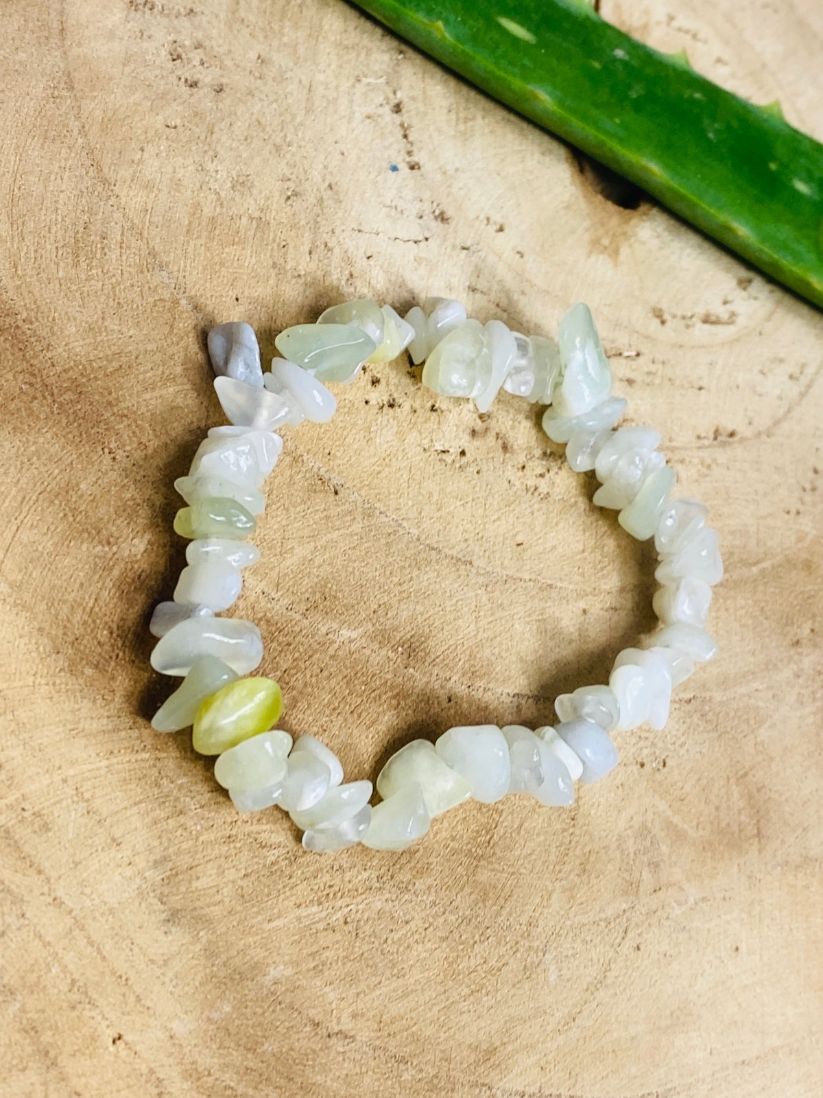 Hellgrünes Serpentin Splitterarmband auf einer Holzplatte 
